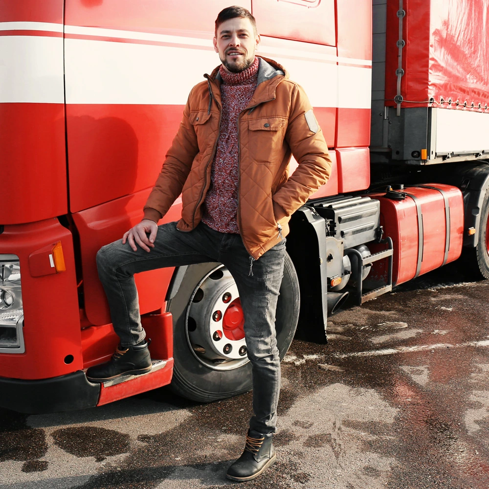 student standing next to red truck and smiling